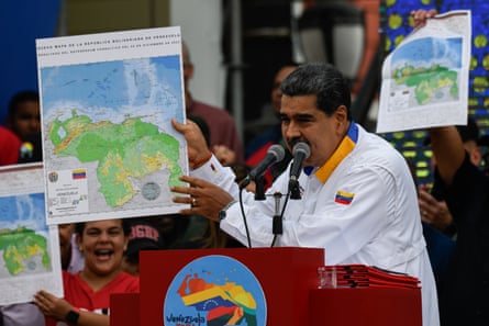 A Latin American man holds up a map to a crowd at a political rally