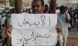 A man holds a placard saying ‘El-Obeid is bleeding’