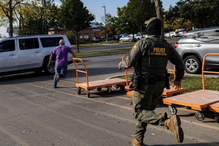 a man in tactical gear chases another man in a parking lot