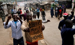 Protesters against Uhuru Kenyatta shout slogans and carry a banner in Mathare, Kenya