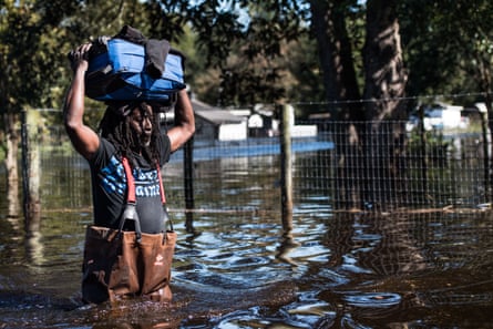A man carries personal items through a flooded street caused by remnants of Hurricane Matthew on October 11, 2016 in Fair Bluff, North Carolina.