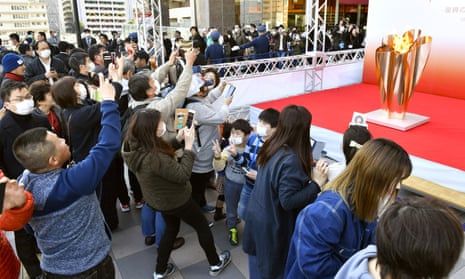 People gather to look at the Olympic flame on display in Sendai