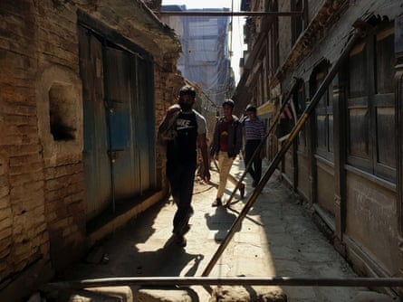 People walk in between iron planks kept in support for houses damaged during massive earthquake 2015 at an alley in Kathmandu