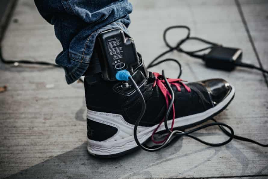 A close-up view of an ankle monitor, which needs to be charged for hours every day.