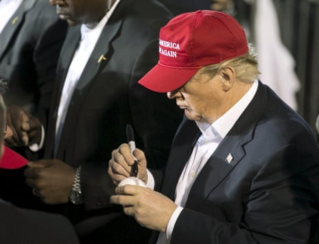 Donald Trump signs a baseball for a supporter at a rally at Madison City Schools Stadium in Madison, Alabama.
