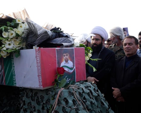 Mourners gather around a flower-covered coffin bearing a photo of the child victim in Iran