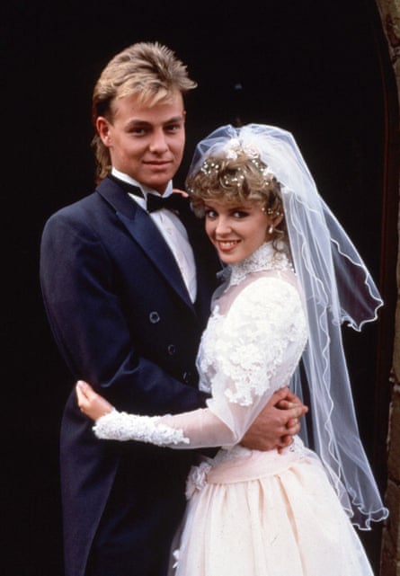 Jason Donovan in a tuxedo and Kylie Minogue in a wedding dress in a scene from Neighbours.