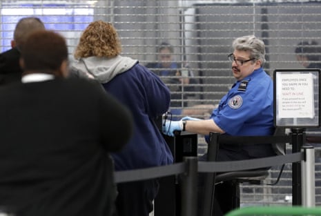 A TSA officer sits while checking IDs at an airport.