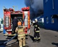 Emergency service workers respond to a Russian strike on a warehouse where black smoke billows