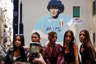 Five women pose for a photo in front of a Maradona mural