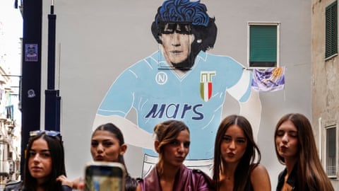 Five women pose for a photo in front of a Maradona mural