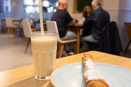 Sweet offering … at Horchatería Fabian. Glass of horchata, farton pastry, customers in background of near empty cafe