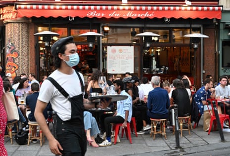 A waiter wearing a face mask serves clients while people eat and have drinks on the terrace of the cafe-restaurant “Le Bar du Marche” in Paris, France on 02 June, 2020.