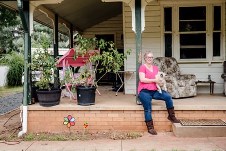 Beck Carter sitting on the edge of a porch in front of a large house, holding her dog