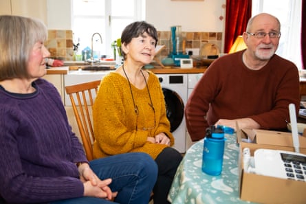 Mark Pugh sits in a kitchen with two women