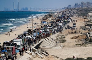 A line of vehicles and people head south along a coastal road