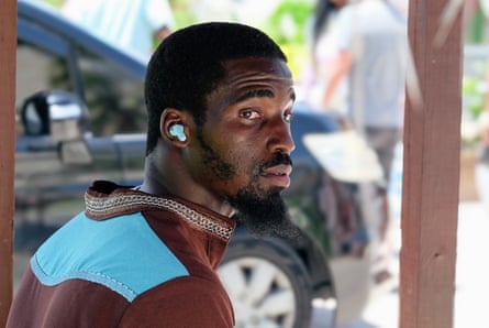 a man in a brown and blue shirt with earphones in his ears looks over his shoulder