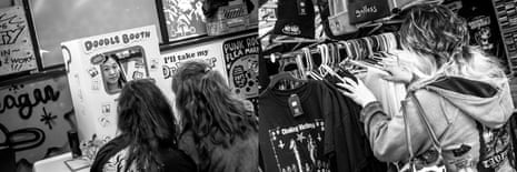 A black-and-white image of people looking at clothing in a booth.