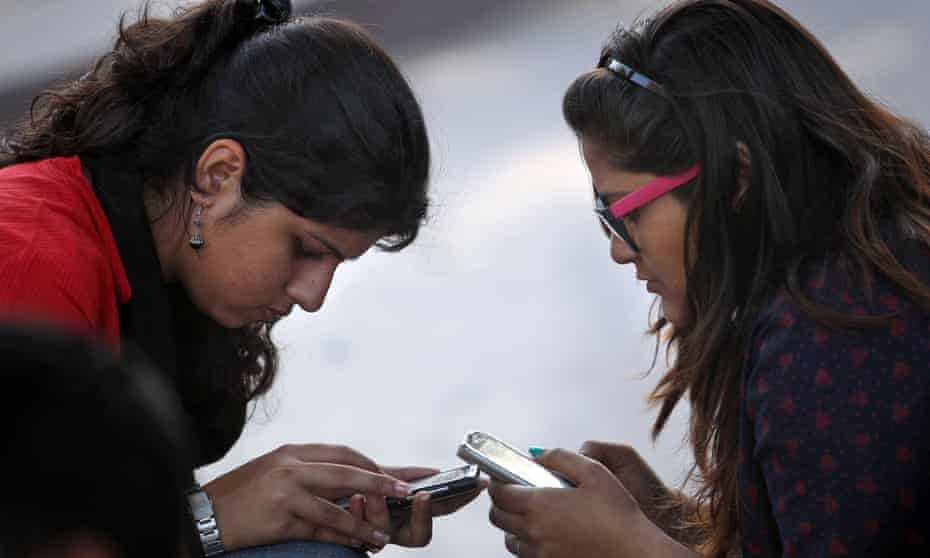 Girls in New Delhi use their mobile phones