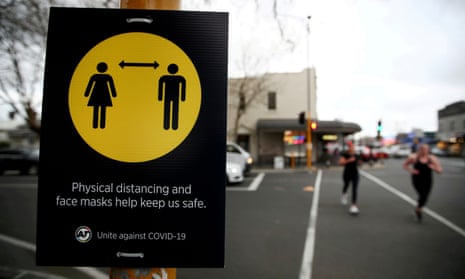 People jog past a social distancing sign in Auckland, New Zealand.