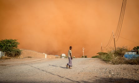 A man walks in front of a sandstorm in Dollow, south-west Somalia