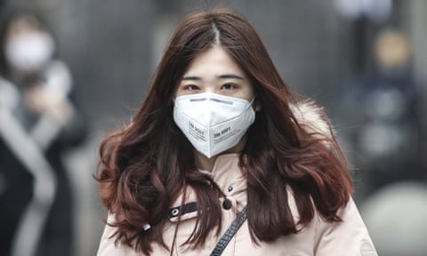 A woman wears a mask in Wuhan where buses, ferries, trains and planes have been prevented from leaving the city.