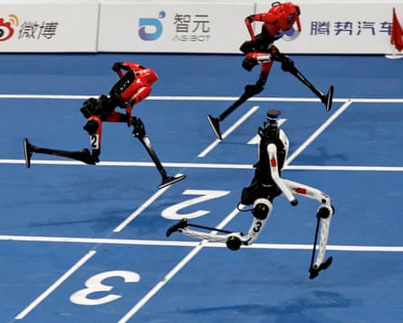 Three humanoid robots cross the finish line at the World Humanoid Robot Games.