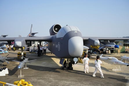 A military plane on the tarmac with two girls in white standing by it