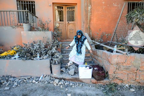 A woman walks through rubble outside a building after Israeli strikes on the town of Naqura in southern Lebanon close to the border