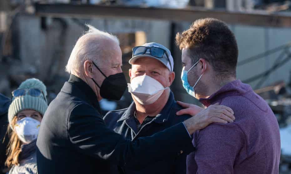 biden puts hand on shoulder of man as another man looks on