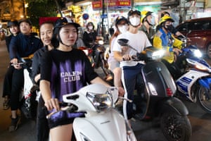 Groups of two people ride a motorbike in Hanoi