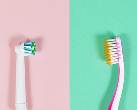 Comparison of electronic and traditional toothbrush side by side on pink and green background