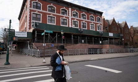 a man in a black coat and black hat in a crosswalk in front of a red brick building