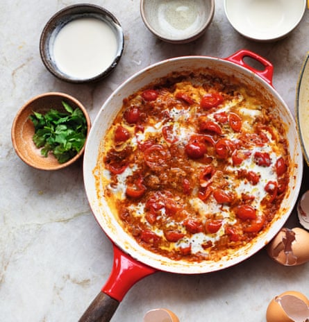 A red pan with eggs and tomatoes