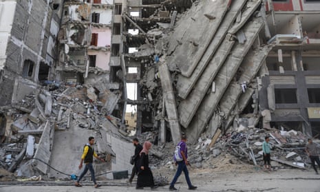 Palestinians walk past destroyed buildings