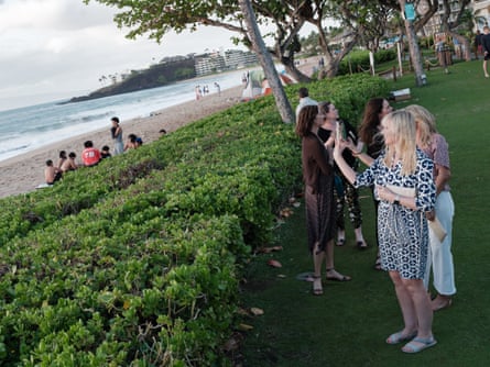 people point cameras amid foliage next to the beach