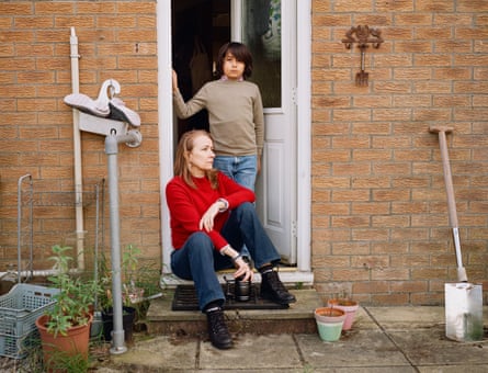 Roksana Aung sits on a doorstep as Alexander stands in the doorway behind her