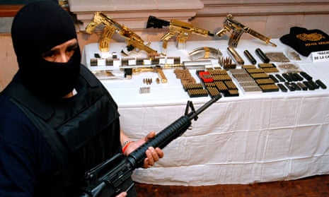 An officer from Mexico’s federal police stands next to weapons seized from the Zetas cartel, partly funded by oil theft.