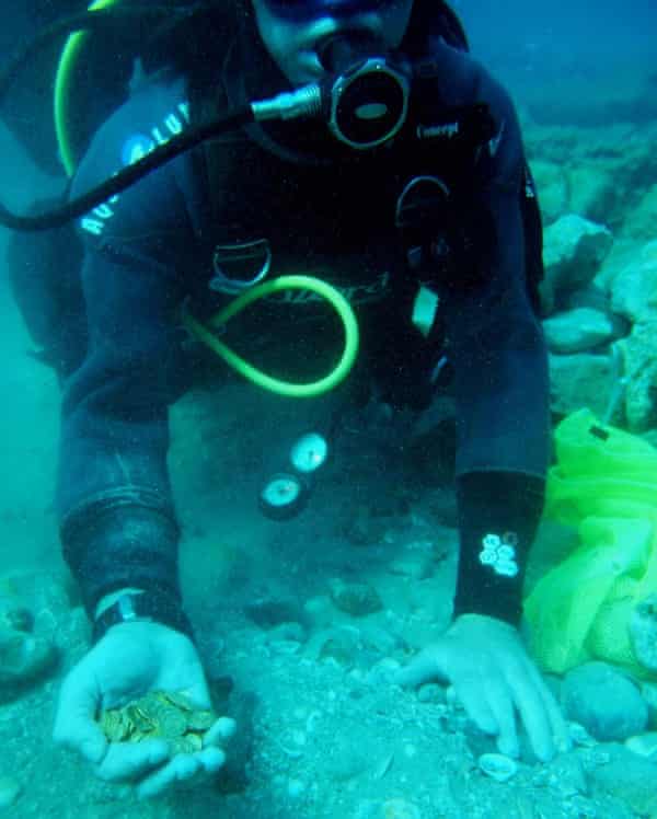 A scuba diver holds some of the gold coins recently found on the seabed in the ancient harbour in the Israeli town of Caesarea. 