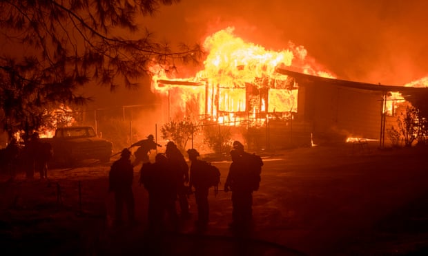 A firefighter carries a hose as a house burns in Oroville, California on Saturday.