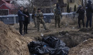 People stand next to a mass grave in Bucha, on the outskirts of Kyiv, Ukraine.