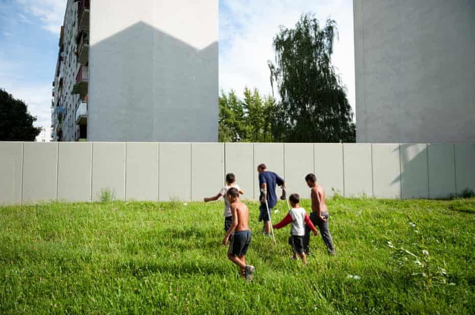 Mihalovce, Slovakia, 2010: Roma people walk towards a 500 metre-long concrete wall erected by the residents of the housing estate beyond to separate the local Roma camp from their residential area.