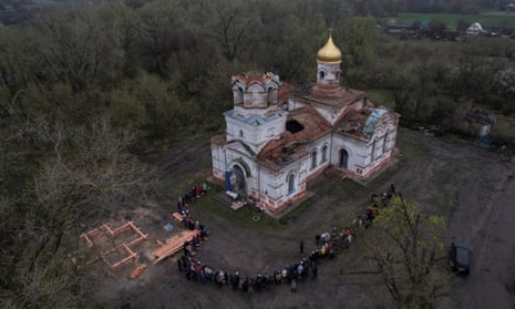 Orthodox priest Serhii sprays holy water on believers during the celebration of the Orthodox Easter in front of a church heavily damaged by Russian forces in the village of Lukashivka, in Chernihiv region