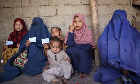 Masooma*, second from left with her children, shows her refugee registration document