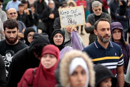 people walk - one holds sign that says ‘keep our children pure’