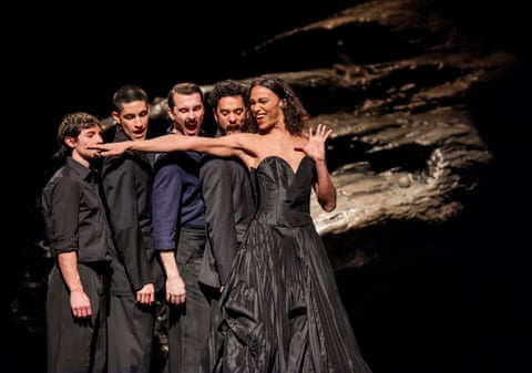 The men stand in a line, pretending to bite her outstretched arm