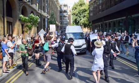 Protesters and photographers crowd the street around a van carrying jailed climate activists in London