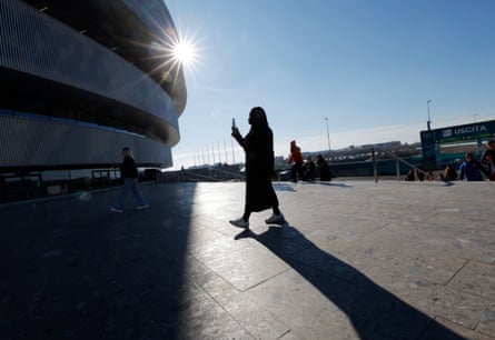 A spectator films the venue as she walks in before the Italy v France round robin match of the women's ice hockey tournament