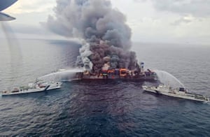 Firefighting tugs spray water onto a burning cargo vessel