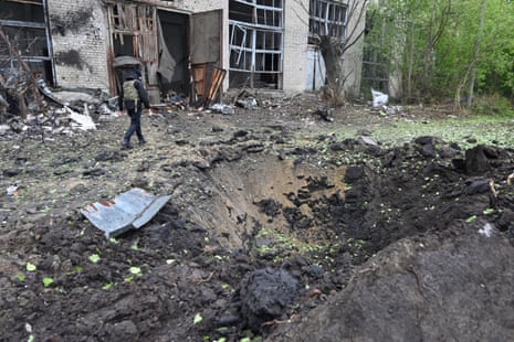 A law enforcement officer walks by a crater next to a damaged building after a missile attack in Kharkiv on Wednesday.